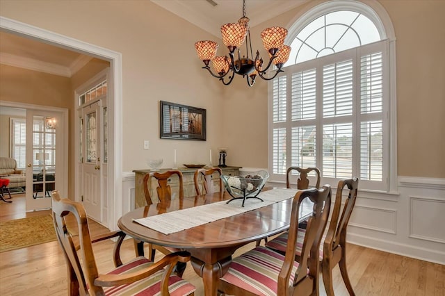 dining room with ornamental molding, a notable chandelier, and light hardwood / wood-style floors