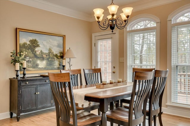 dining area with ornamental molding, a notable chandelier, light hardwood / wood-style flooring, and a wealth of natural light