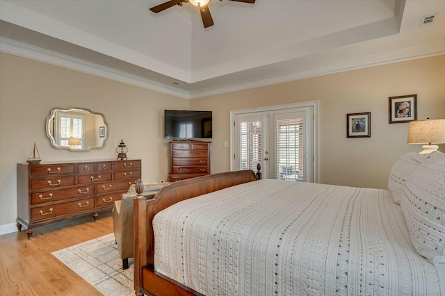 bedroom with ceiling fan, french doors, a tray ceiling, light hardwood / wood-style flooring, and access to exterior