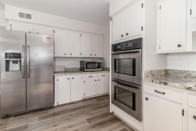 3247 Ramsgate Rd, Augusta, GA 30909 - kitchen featuring appliances with stainless steel finishes, white cabinets, decorative backsplash, light wood-style floors, and light stone counters