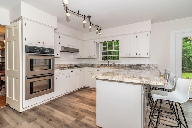 3247 Ramsgate Rd, Augusta, GA 30909 - kitchen featuring double oven, a peninsula, under cabinet range hood, and white cabinets