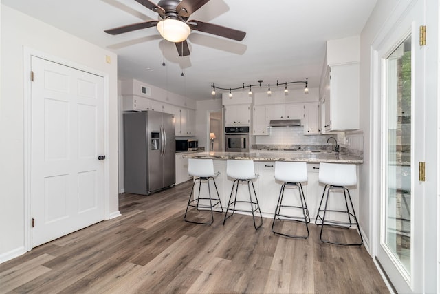 3247 Ramsgate Rd, Augusta, GA 30909 - kitchen featuring appliances with stainless steel finishes, a peninsula, white cabinets, and decorative backsplash