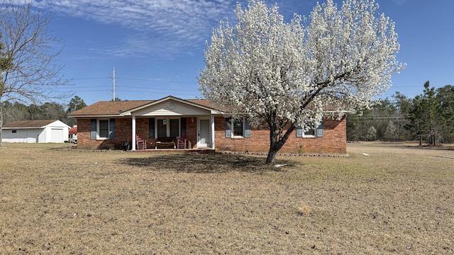 ranch-style home featuring covered porch, a front lawn, and brick siding