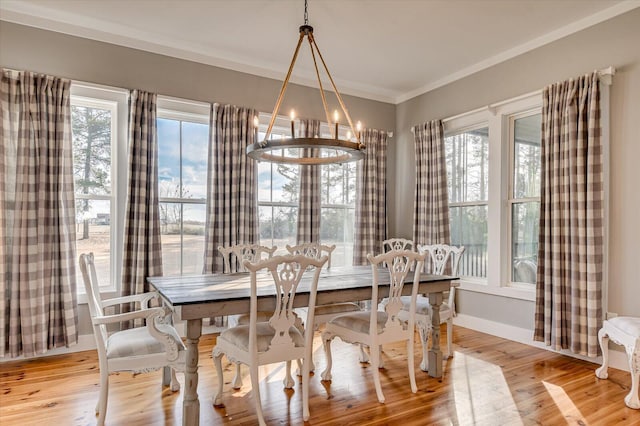 dining room with ornamental molding, light wood-type flooring, and a notable chandelier