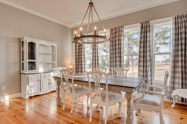 dining room featuring ornamental molding, light wood-type flooring, and a chandelier