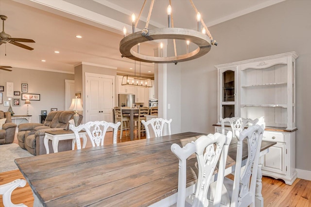 dining space with ceiling fan with notable chandelier, light hardwood / wood-style floors, and crown molding