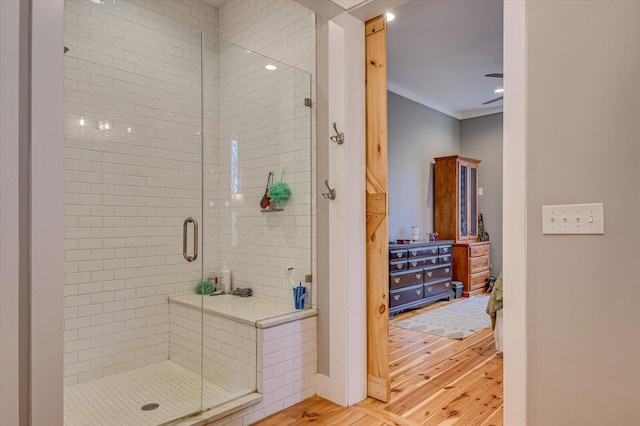 bathroom with crown molding, a shower with shower door, and wood-type flooring