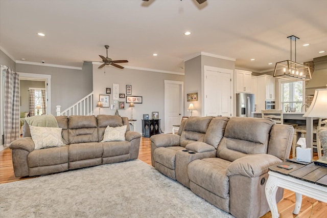 living room featuring ceiling fan, light wood-type flooring, and crown molding