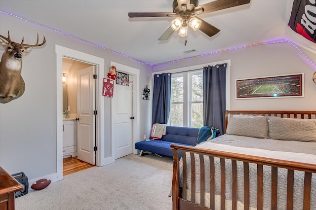 carpeted bedroom featuring ensuite bath and ceiling fan