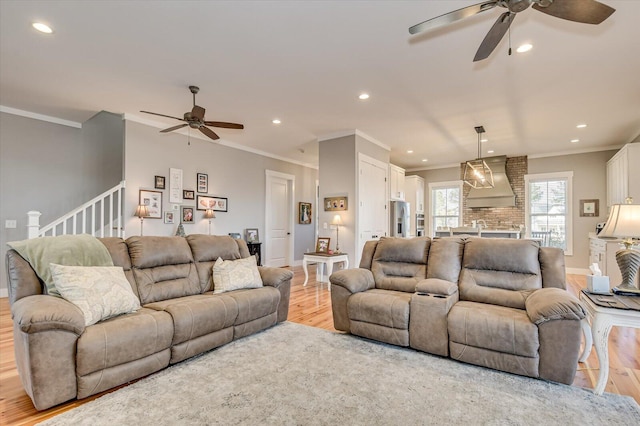 living room with ceiling fan, crown molding, and light hardwood / wood-style flooring