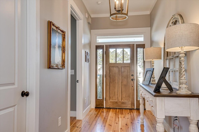 foyer entrance featuring light hardwood / wood-style floors, crown molding, and a chandelier