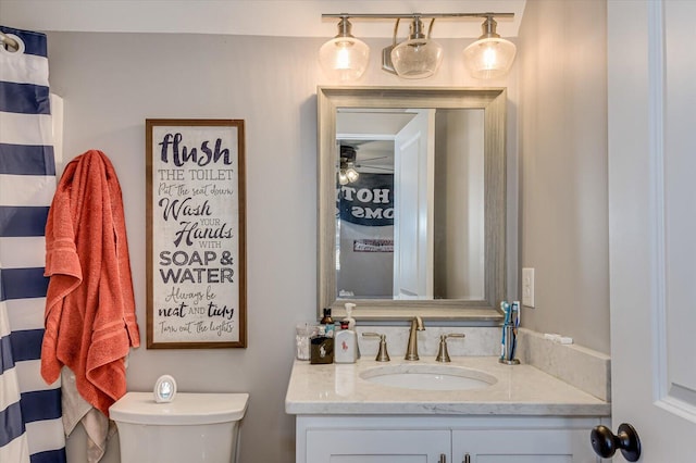 bathroom featuring toilet, vanity, and ceiling fan