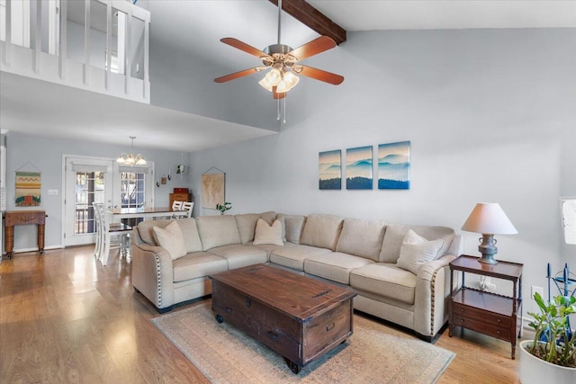 living room featuring french doors, beamed ceiling, wood-type flooring, and ceiling fan with notable chandelier