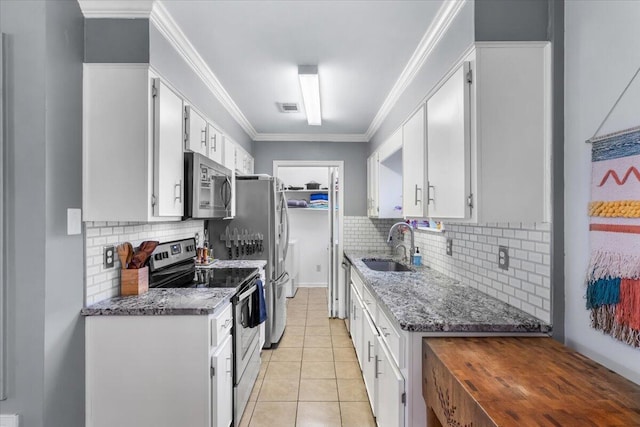 kitchen featuring appliances with stainless steel finishes, sink, light tile patterned floors, dark stone countertops, and white cabinets