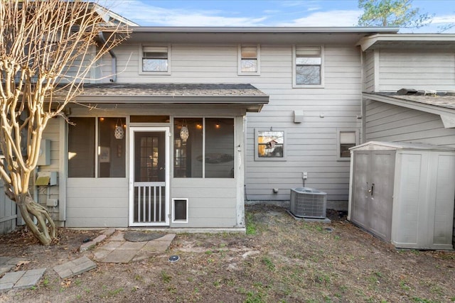 back of property with central AC, a sunroom, and a storage unit