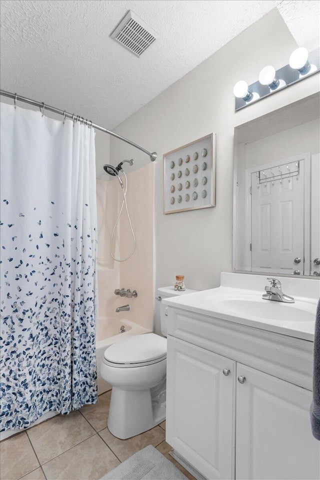 full bathroom featuring tile patterned floors, vanity, a textured ceiling, shower / tub combo with curtain, and toilet