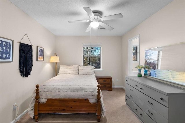 bedroom with ceiling fan, light colored carpet, and a textured ceiling