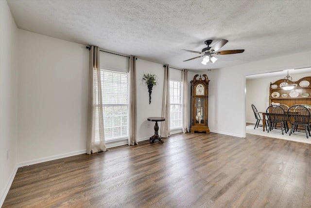 interior space featuring baseboards, a textured ceiling, a ceiling fan, and wood finished floors