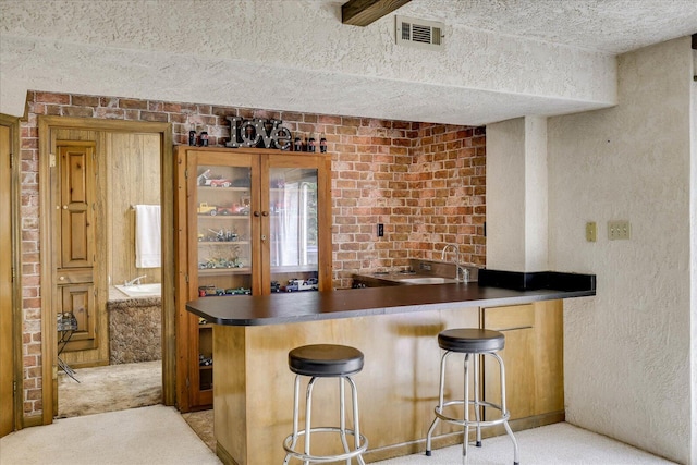 bar with visible vents, light carpet, wet bar, a textured ceiling, and a sink