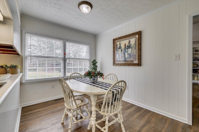 dining space with visible vents, baseboards, ornamental molding, a textured ceiling, and dark wood-style flooring