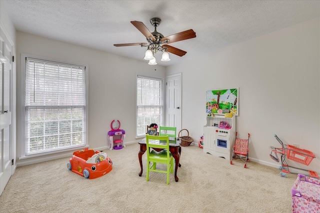 playroom featuring baseboards, carpet floors, a textured ceiling, and a ceiling fan