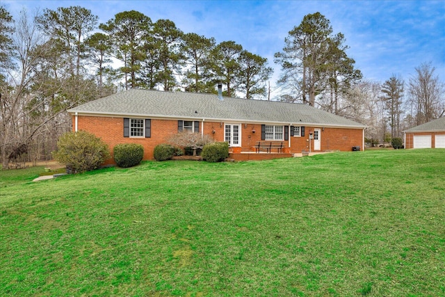 view of front of house with brick siding, a detached garage, and a front yard