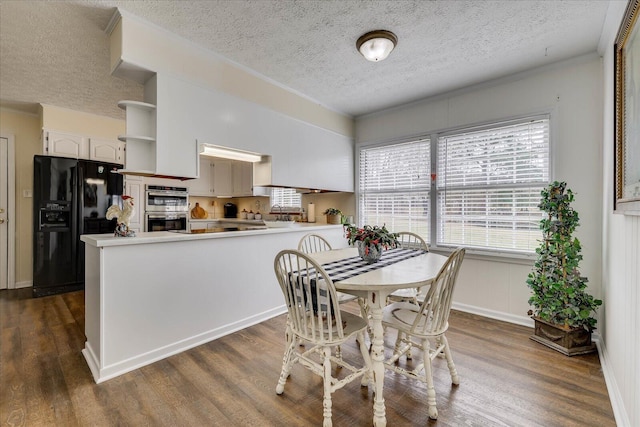 dining area with a textured ceiling, dark wood-style floors, and crown molding