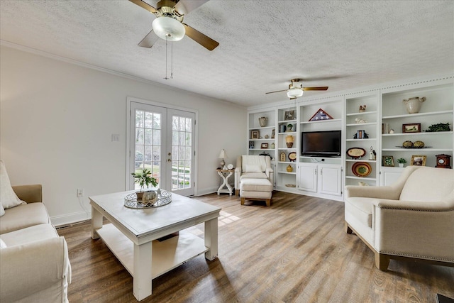 living area with french doors, a textured ceiling, baseboards, and wood finished floors