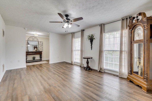 unfurnished living room with visible vents, a textured ceiling, a healthy amount of sunlight, and wood finished floors