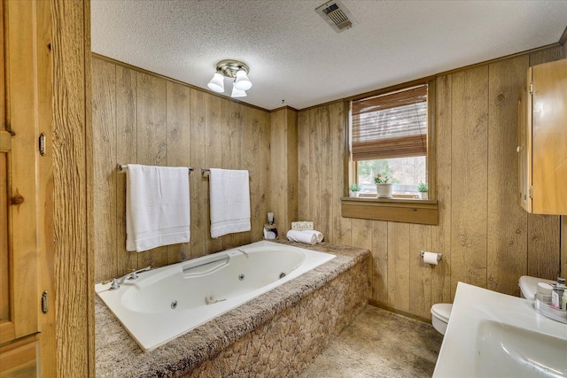 full bath featuring visible vents, wood walls, toilet, a whirlpool tub, and a textured ceiling