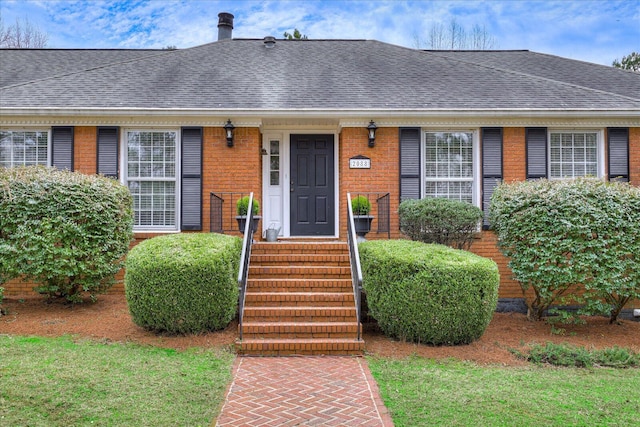 view of front facade with brick siding and a shingled roof