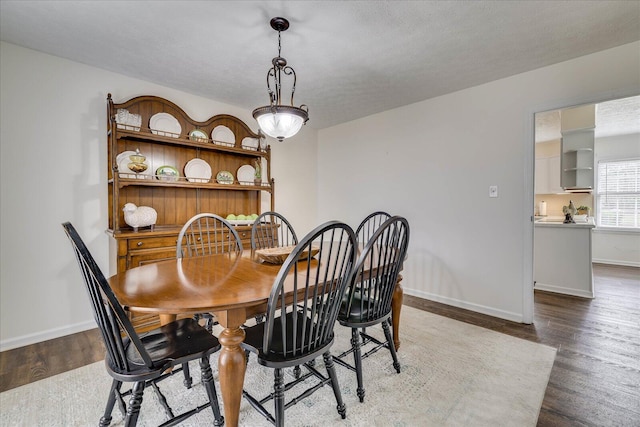 dining area featuring a textured ceiling, baseboards, and wood finished floors