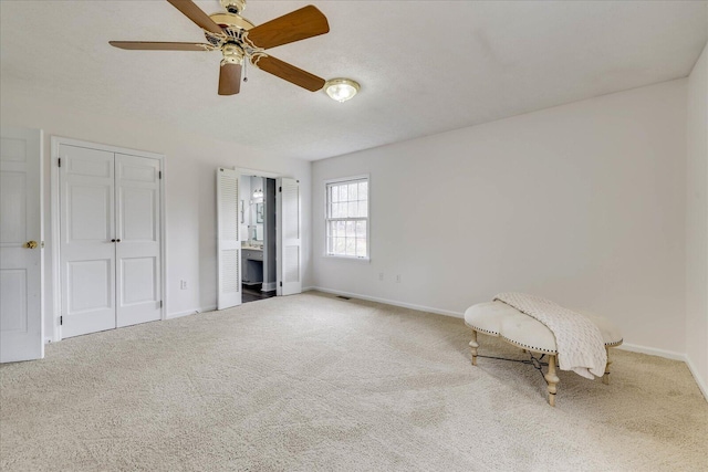 unfurnished bedroom featuring connected bathroom, baseboards, carpet, and ceiling fan