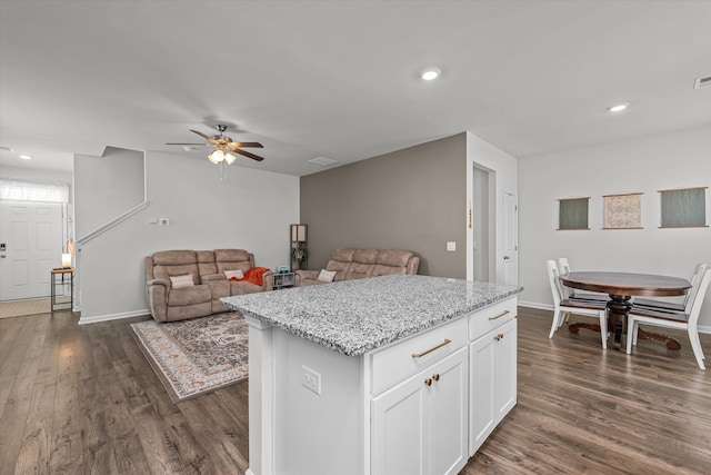 kitchen featuring a kitchen island, dark hardwood / wood-style floors, white cabinetry, ceiling fan, and light stone countertops