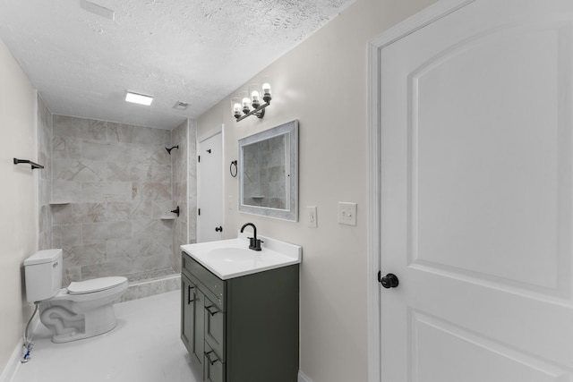 bathroom with toilet, vanity, a textured ceiling, and tiled shower