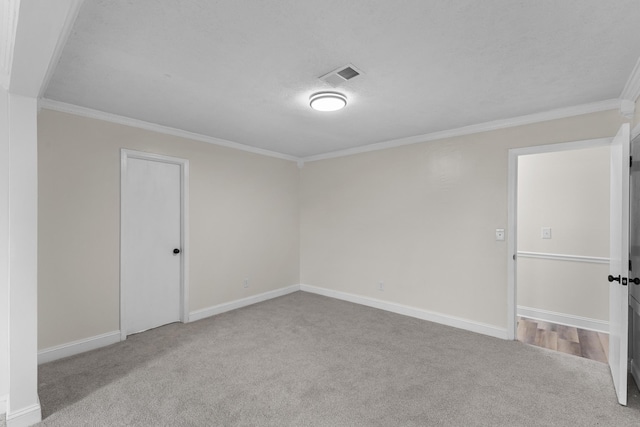 unfurnished room featuring light colored carpet, ornamental molding, and a textured ceiling