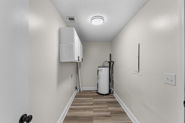 laundry area featuring cabinets, electric panel, light hardwood / wood-style floors, and water heater