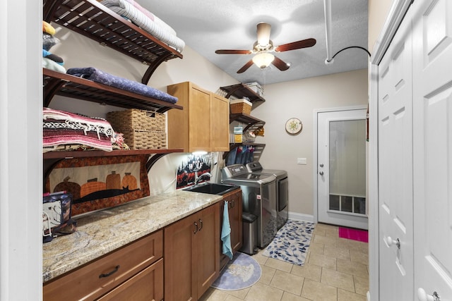 clothes washing area with ceiling fan, washer and clothes dryer, light tile patterned floors, cabinet space, and a sink