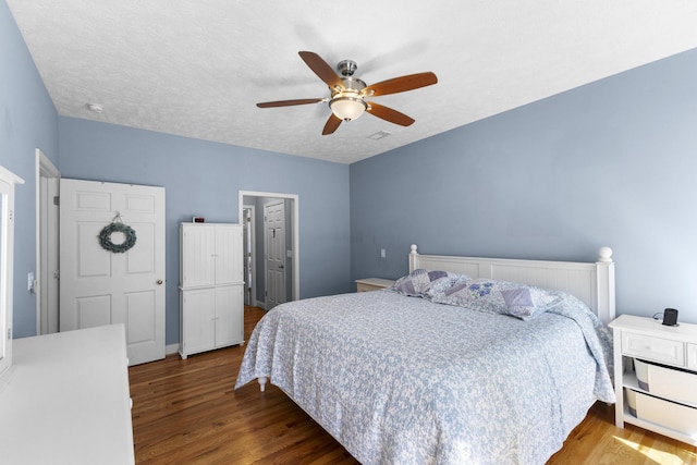 bedroom with a textured ceiling, a ceiling fan, and wood finished floors