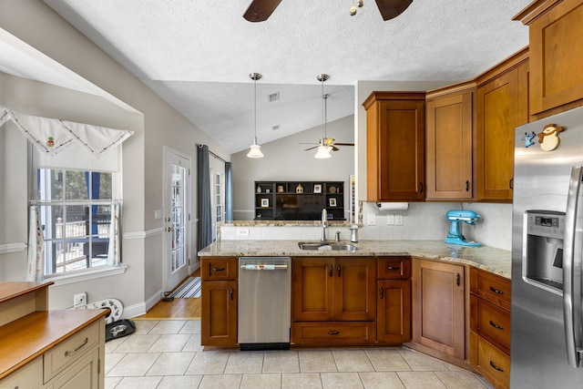 kitchen featuring a ceiling fan, a peninsula, a sink, stainless steel appliances, and brown cabinets