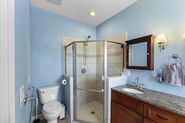 full bathroom with vanity, toilet, a stall shower, and a textured ceiling