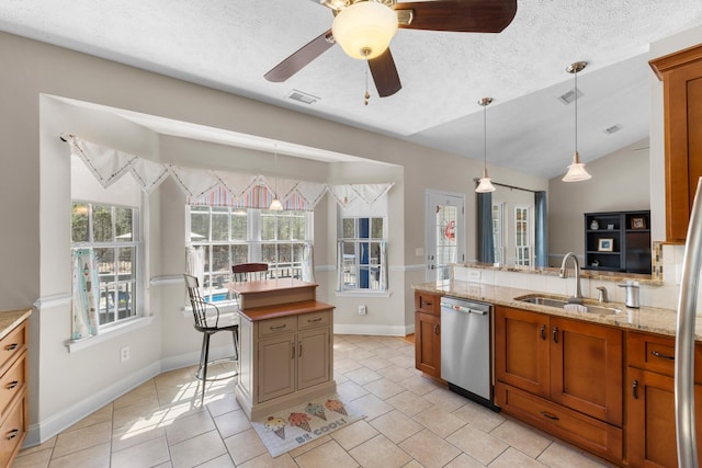 kitchen featuring brown cabinetry, visible vents, a sink, vaulted ceiling, and stainless steel dishwasher