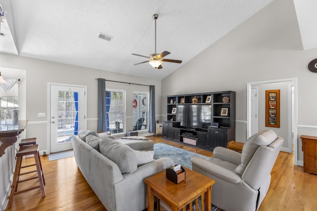 living area with visible vents, light wood-style flooring, a textured ceiling, and a ceiling fan