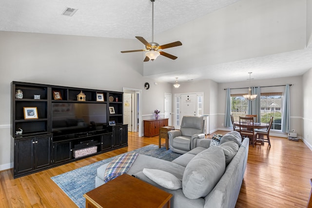 living room with visible vents, baseboards, ceiling fan with notable chandelier, and light wood finished floors