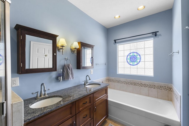 full bath with a sink, recessed lighting, a bath, and double vanity