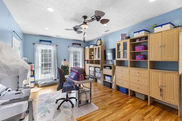 office space with ceiling fan, plenty of natural light, a textured ceiling, and light wood-style flooring