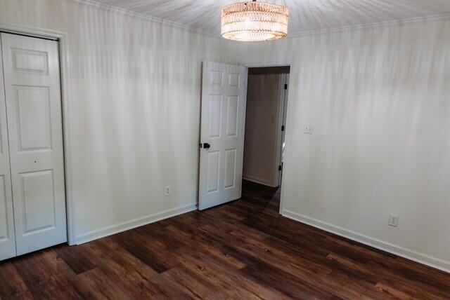 8643 Underwood Rd, Mitchell, GA 30820 - empty room with a chandelier, baseboards, and dark wood-style flooring