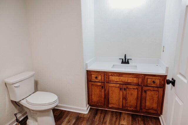 8643 Underwood Rd, Mitchell, GA 30820 - half bathroom featuring wood finished floors, vanity, toilet, and baseboards