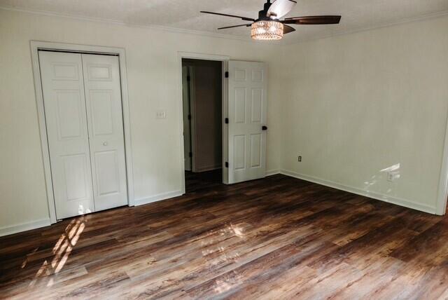 8643 Underwood Rd, Mitchell, GA 30820 - unfurnished bedroom featuring ornamental molding, dark wood-style flooring, baseboards, and a closet