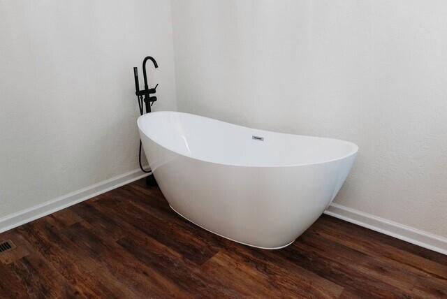 8643 Underwood Rd, Mitchell, GA 30820 - bathroom featuring a freestanding tub, wood finished floors, and baseboards